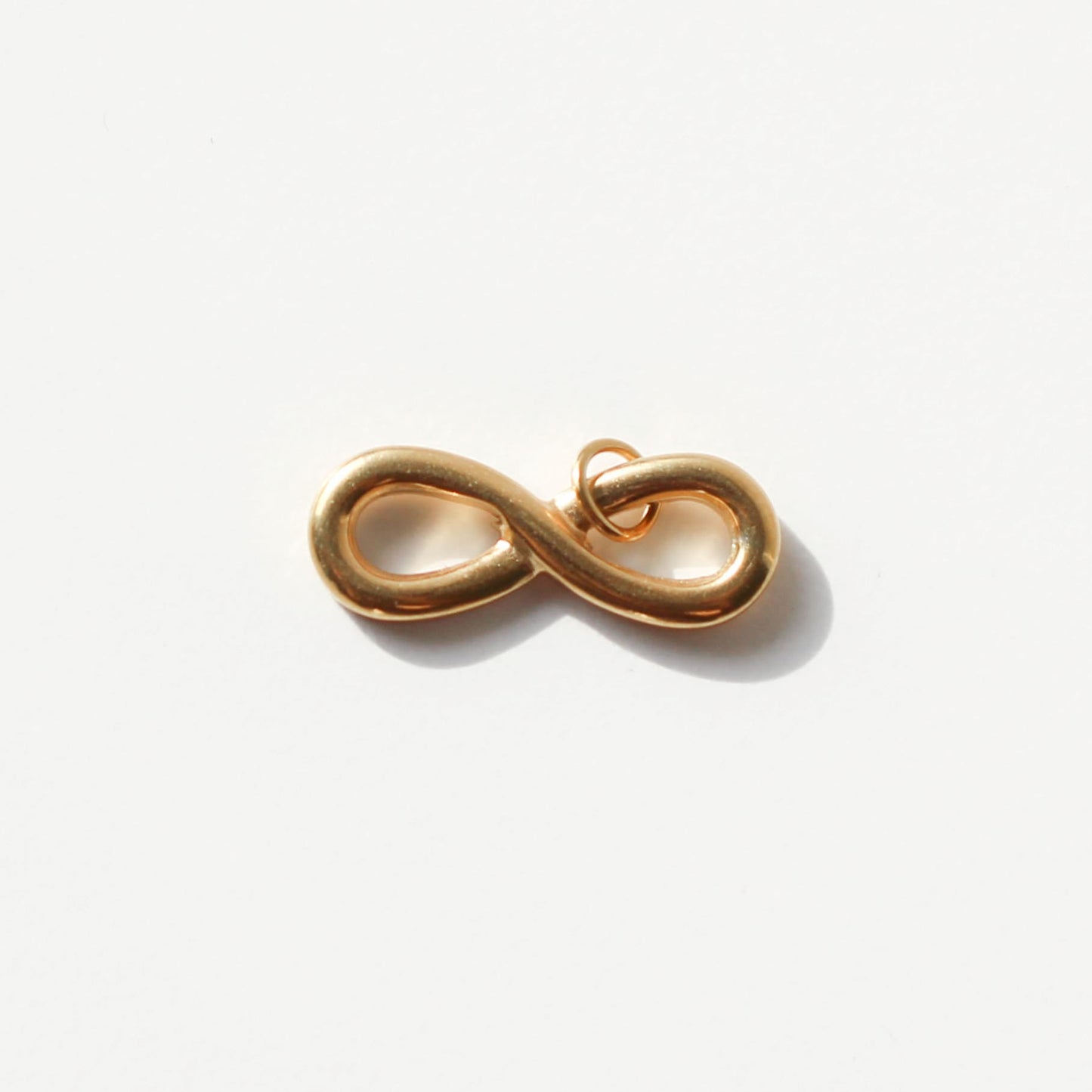 Gold infinity symbol charm on a white background