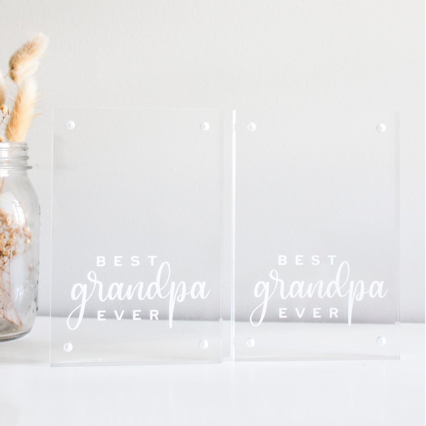 Two clear acrylic blocks with 'Best Grandpa Ever' text and a jar with dried plants on a light background.