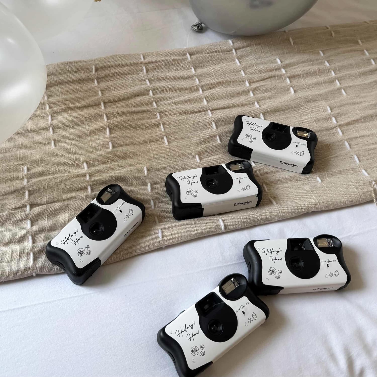 Five instant cameras for a bachelorette party on a textured surface with a neutral background