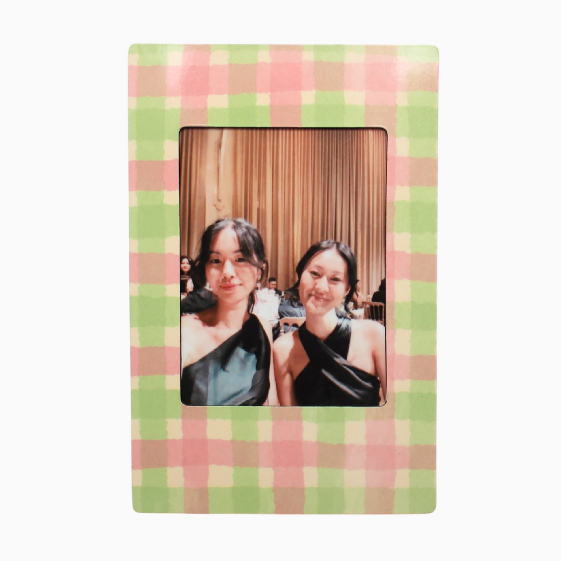 Two women posing together with a green and pink magnetic polaroid frame