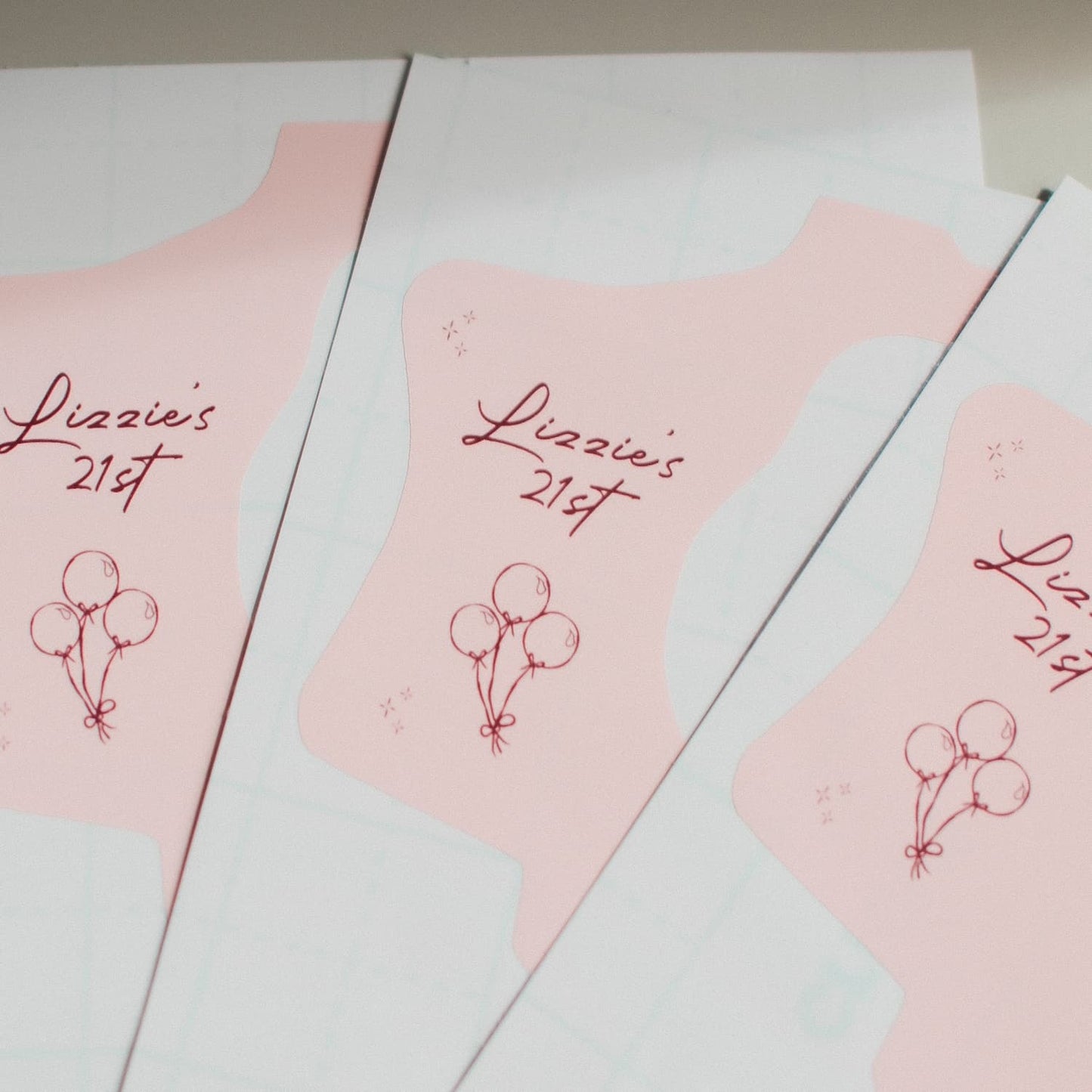 Three pink disposable camera wraps with 'Lizzie's 21st' text and balloon design on a white background