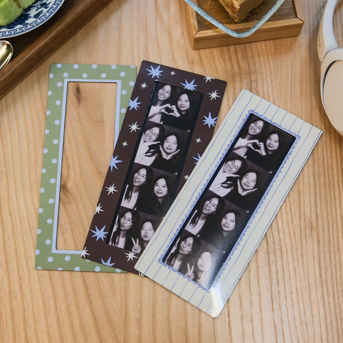 Three magnetic photo booth frames with collage of faces on a wooden surface