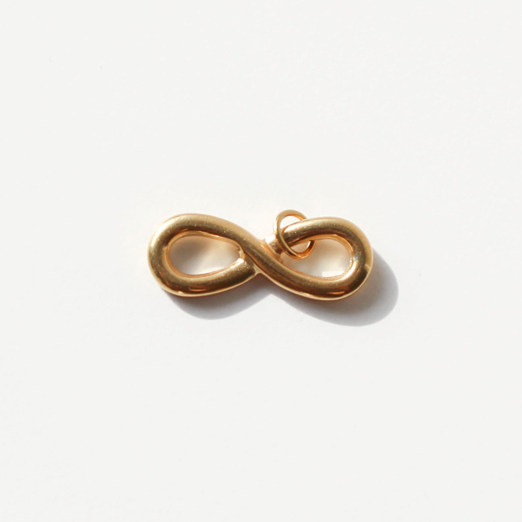 Gold infinity symbol charm on a white background