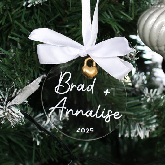 Personalised acrylic Christmas ornament with 'Brad + Analise 2025' text on a tree.