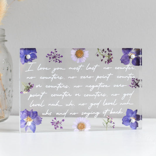 Decorative glass block with floral designs and a romantic message on a light gray background.