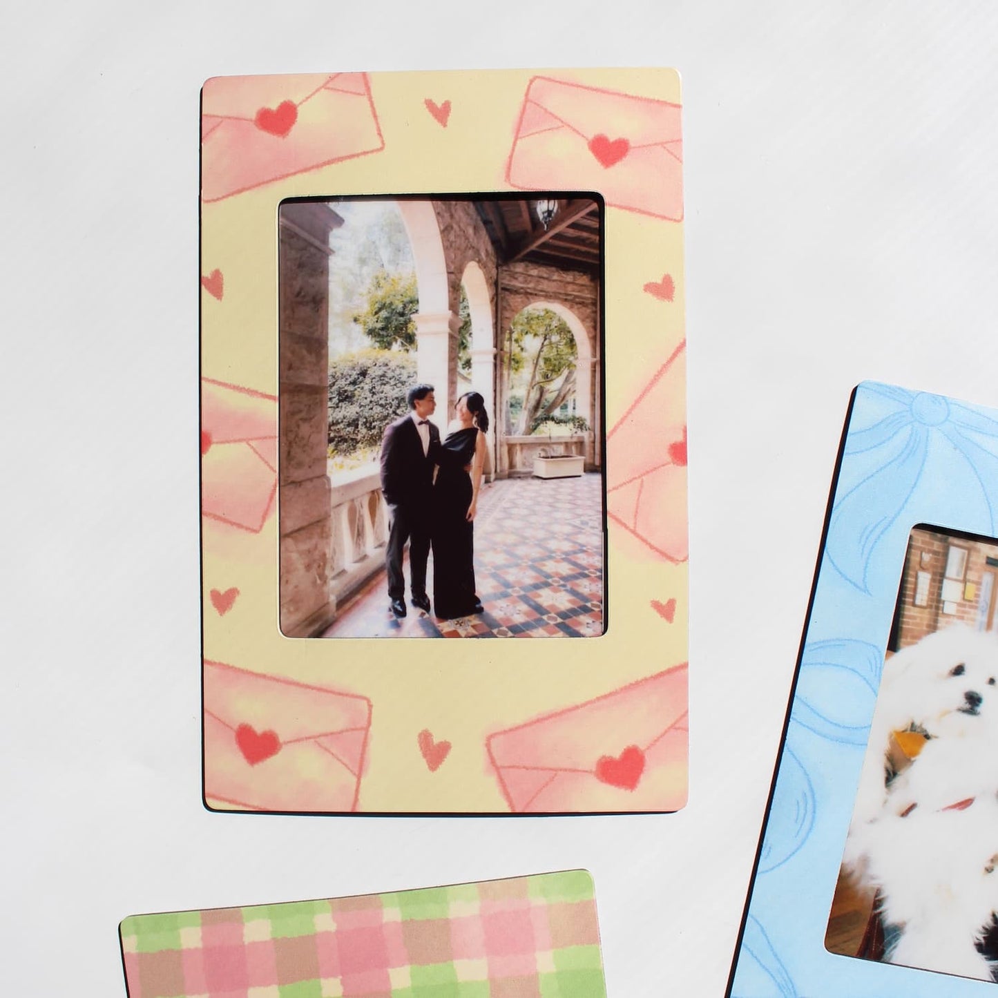 Decorative magnetic photo frame with heart designs and a couple in an outdoor setting, next to a magnetic photo frame displaying a dog photo.