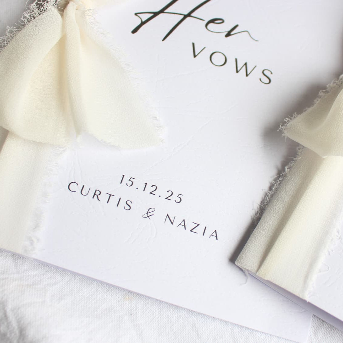 Two wedding vow books with ribbons, personalized for Curtis & Nazia, on a white surface.