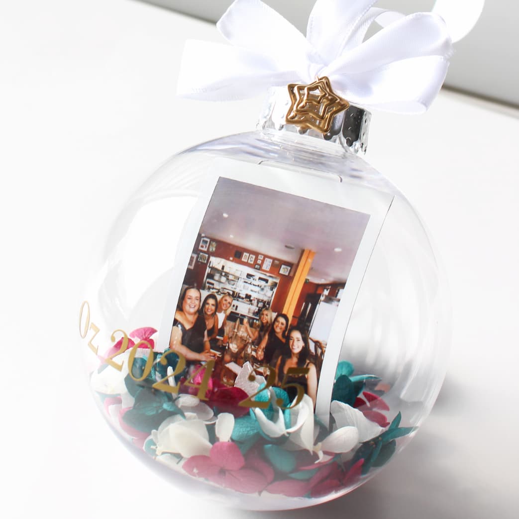 Clear Christmas ornament with a photo inside and decorative elements on a white background