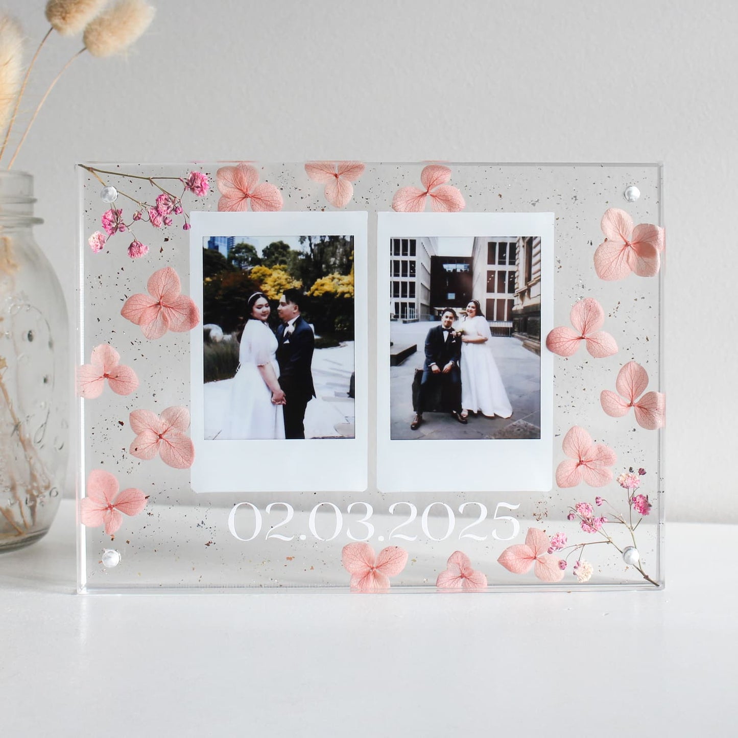 Acrylic photo frame with floral decorations and two wedding photos inside.