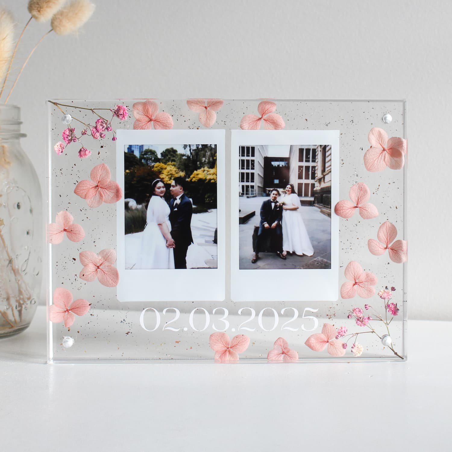Acrylic photo frame with floral decorations and two wedding photos inside.