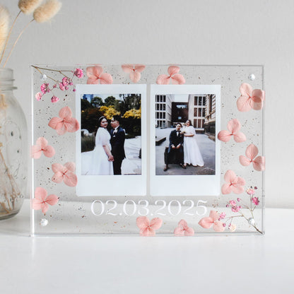 Acrylic photo frame with floral decorations and two wedding photos inside.